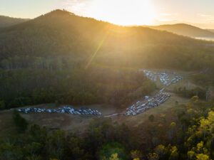 “People setting up campsites during the Gympie Music Muster Rope Off event, with tents and caravans being arranged, and a festive atmosphere as music lovers gather to secure their spots for the festival.”