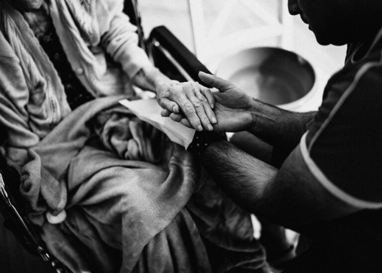 https://www.pexels.com/photo/black-and-white-photo-of-a-man-holding-the-hand-of-an-elderly-woman-on-a-wheelchair-16364308/